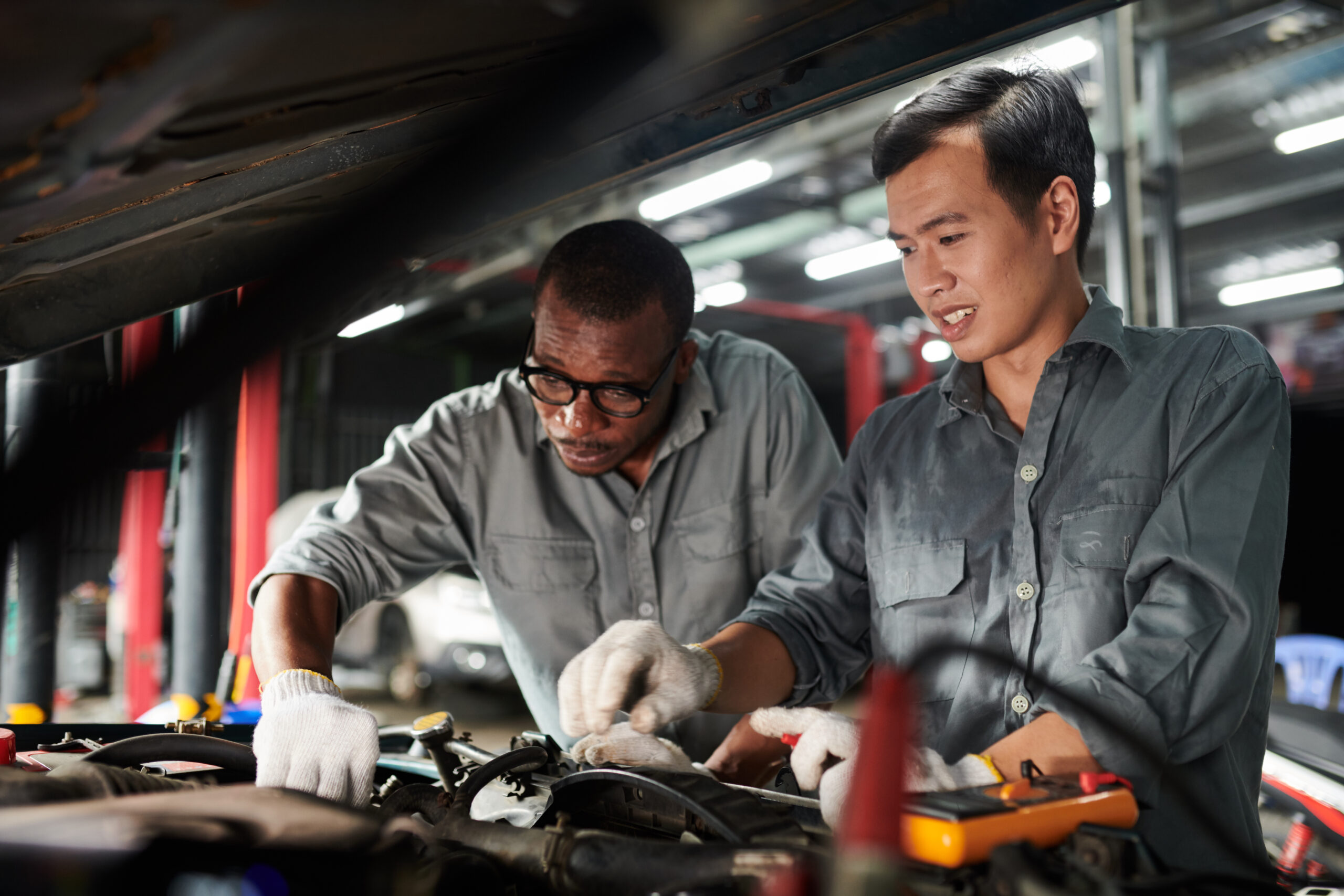 Team of car mechanics in uniform checking car engine
